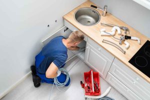 plumber unclogging a kitchen drain